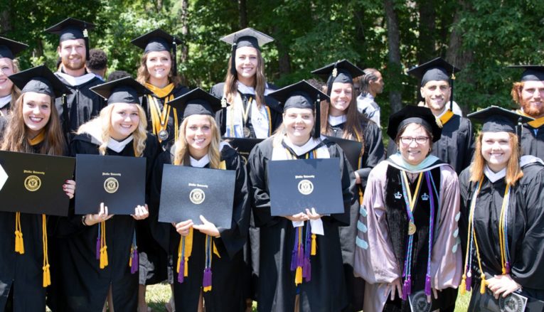 Group of graduates smiling and holding diplomas